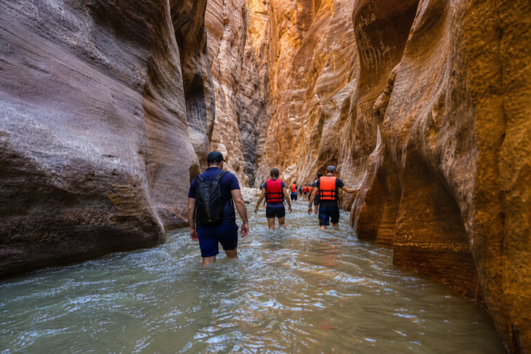 Hikers walking through canyon water on the Wadi Al Mujib Siq Trail